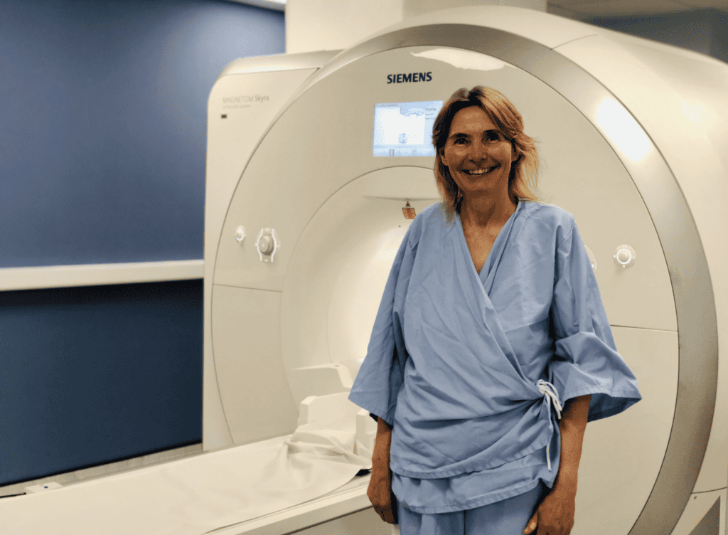 Sue Jacobs smiling in front of an MRI scanner