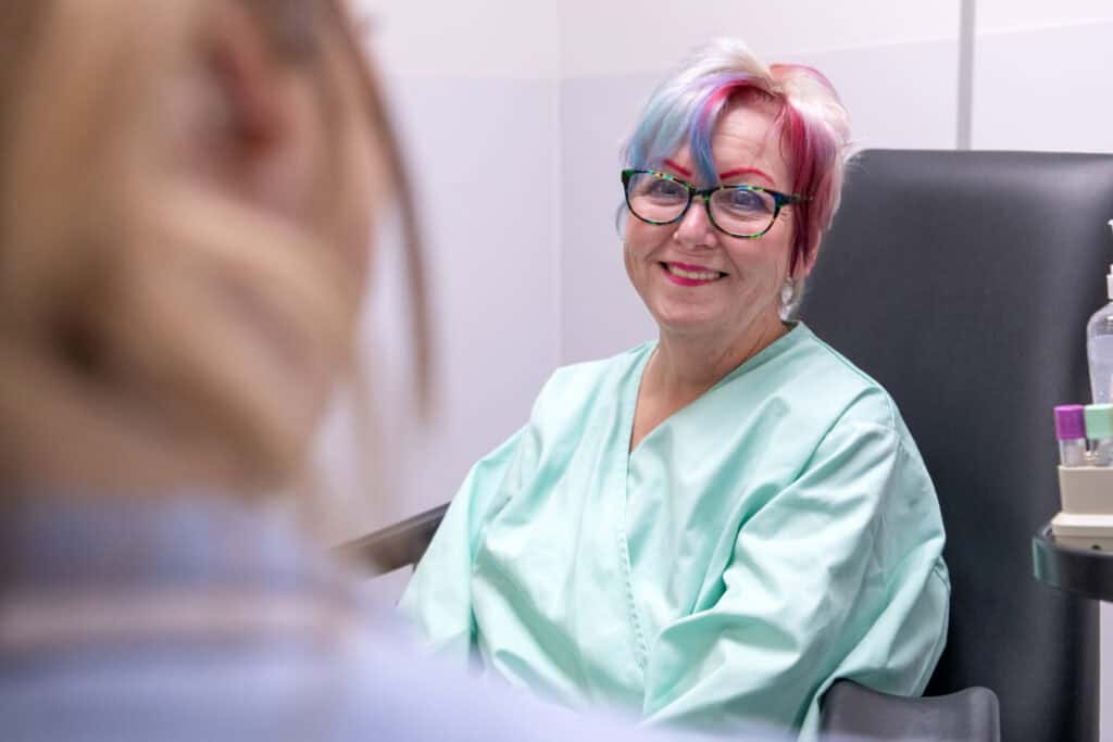 A participant sits talking to a nurse, smiling