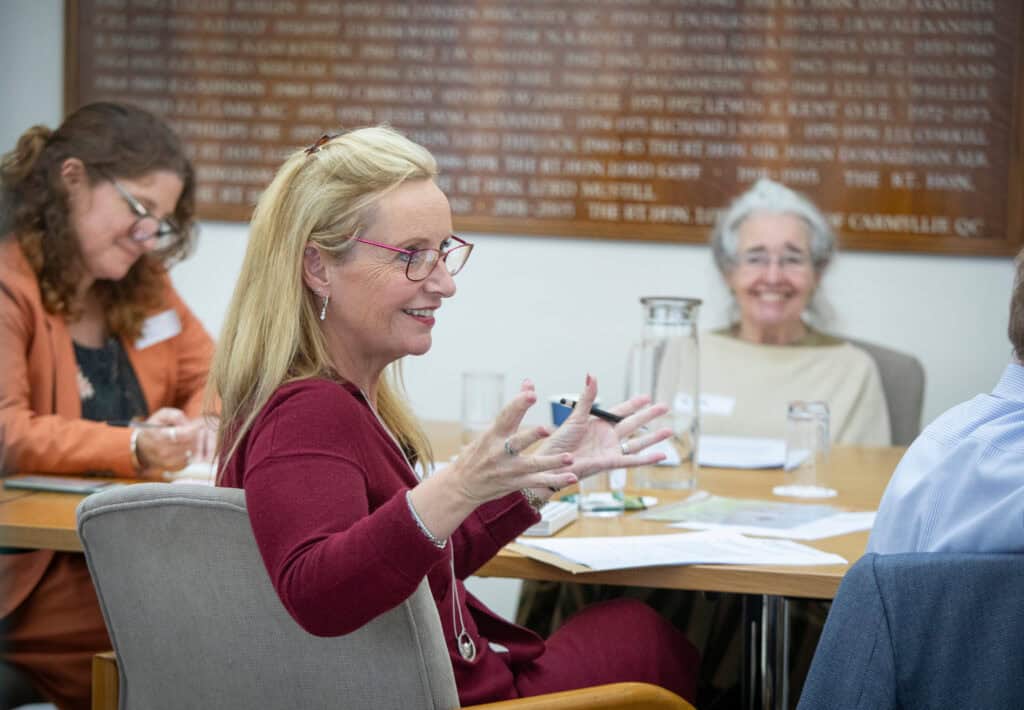 A member of the Participant Advisory Group explains something with others sat looking on
