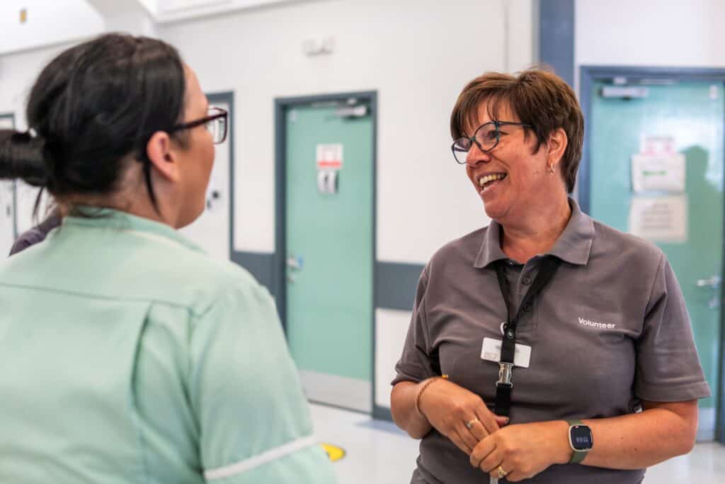 Two medical staff talk in a hospital corridor