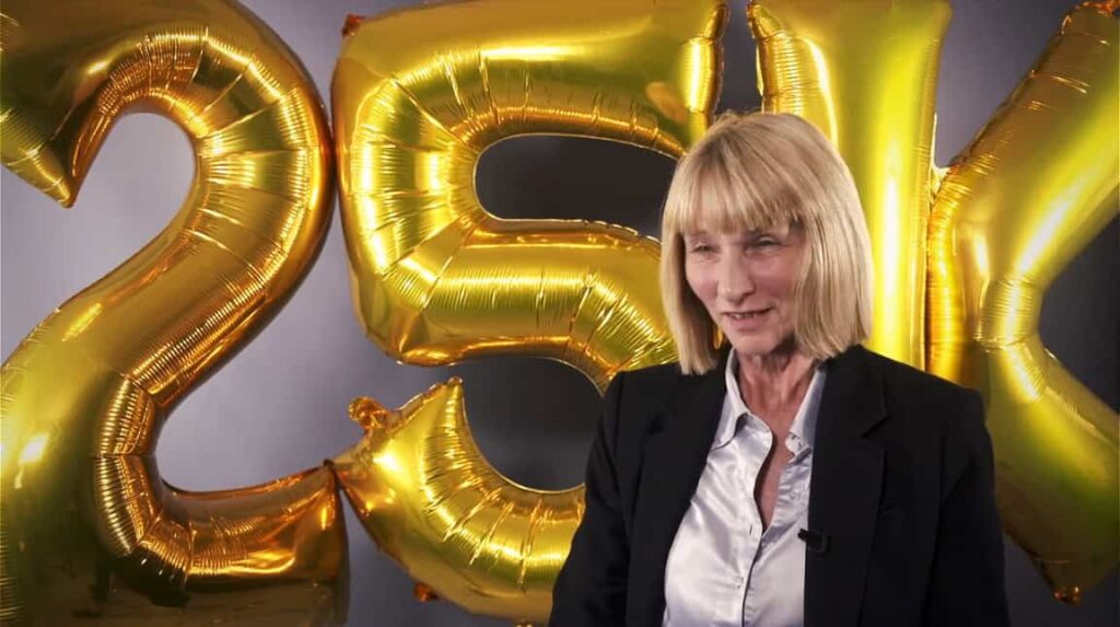 The 25,000 imaging study participant sits in front of balloons saying 25k