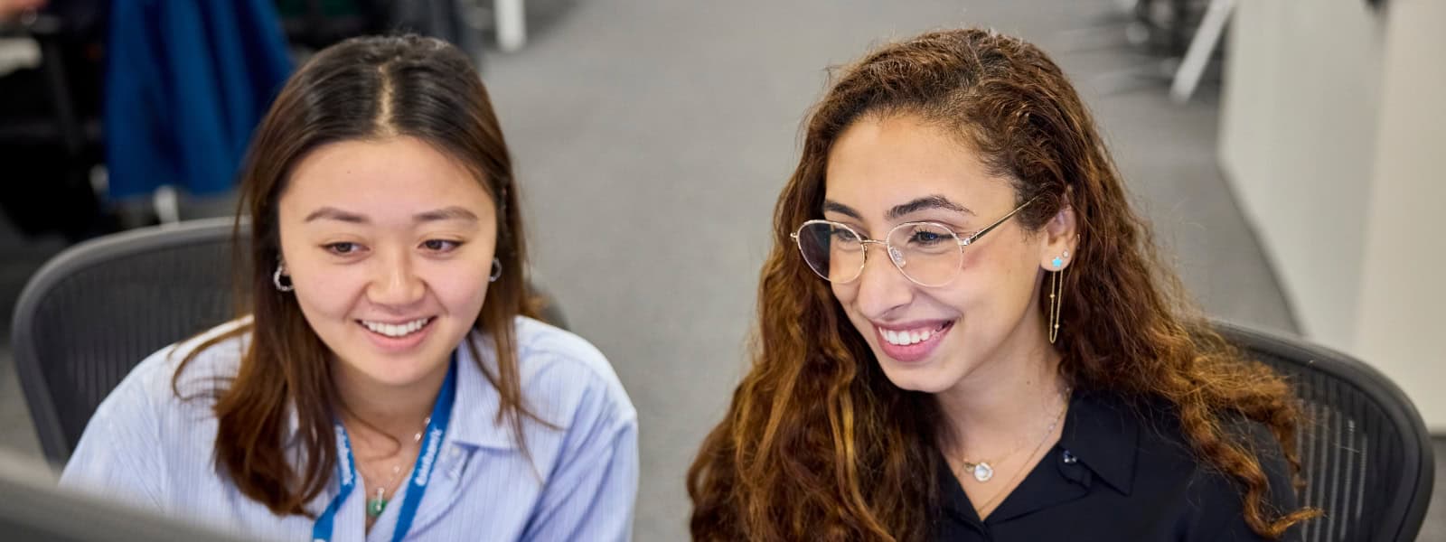 Two women look at a computer screen together, smiling