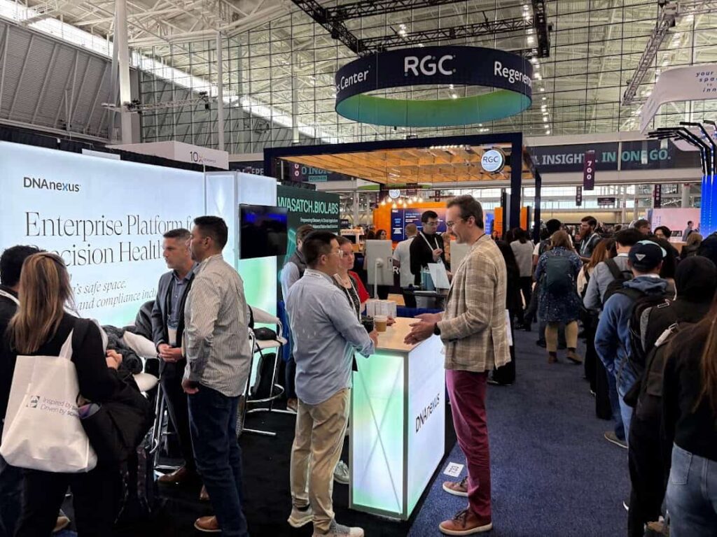 People attending an event mingle and chat at different stands from different organisations, including UK Biobank partner DNAnexus